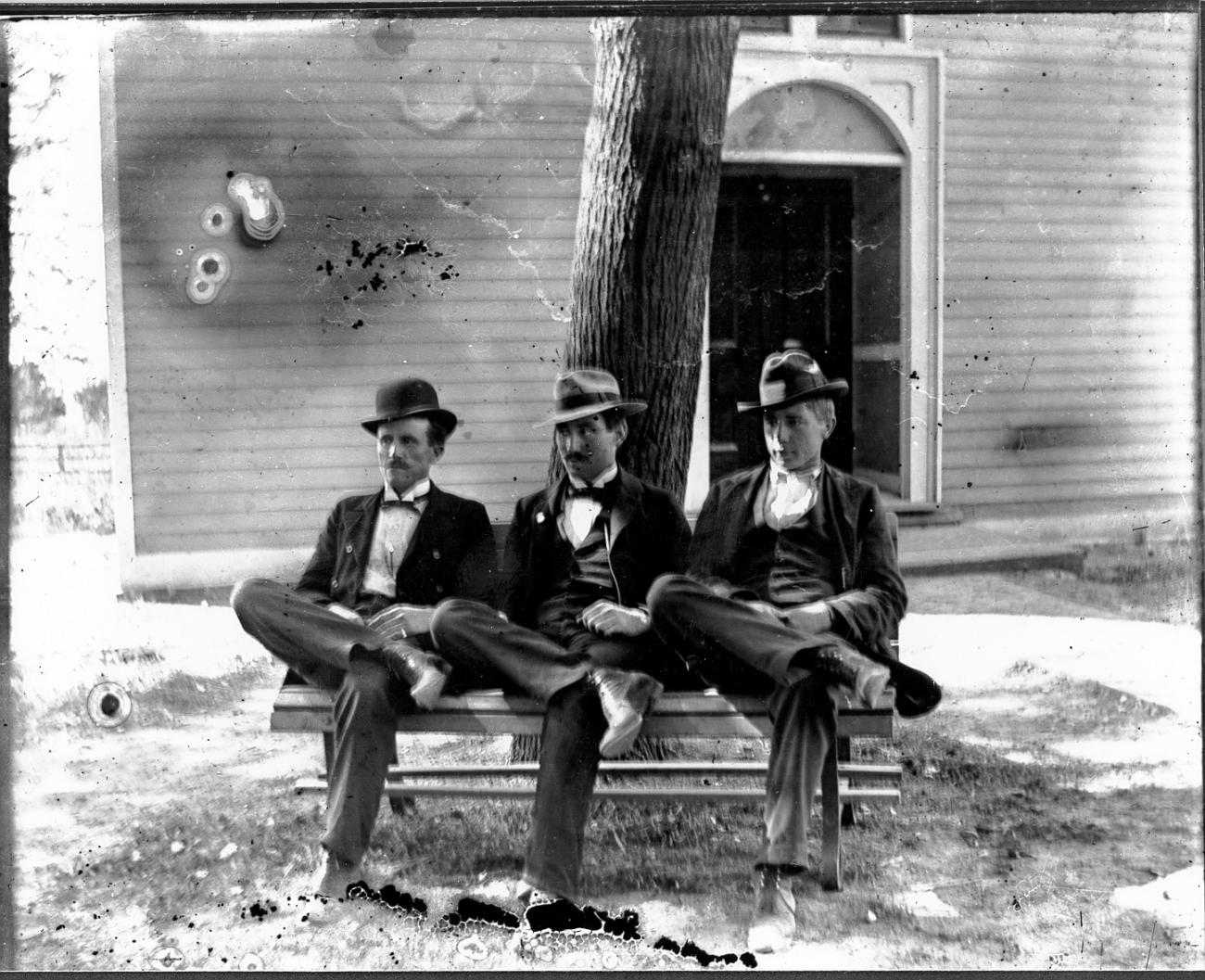 Three men sitting on a bench in front of the Worthington Presbyterian Church ca 1880-1900)