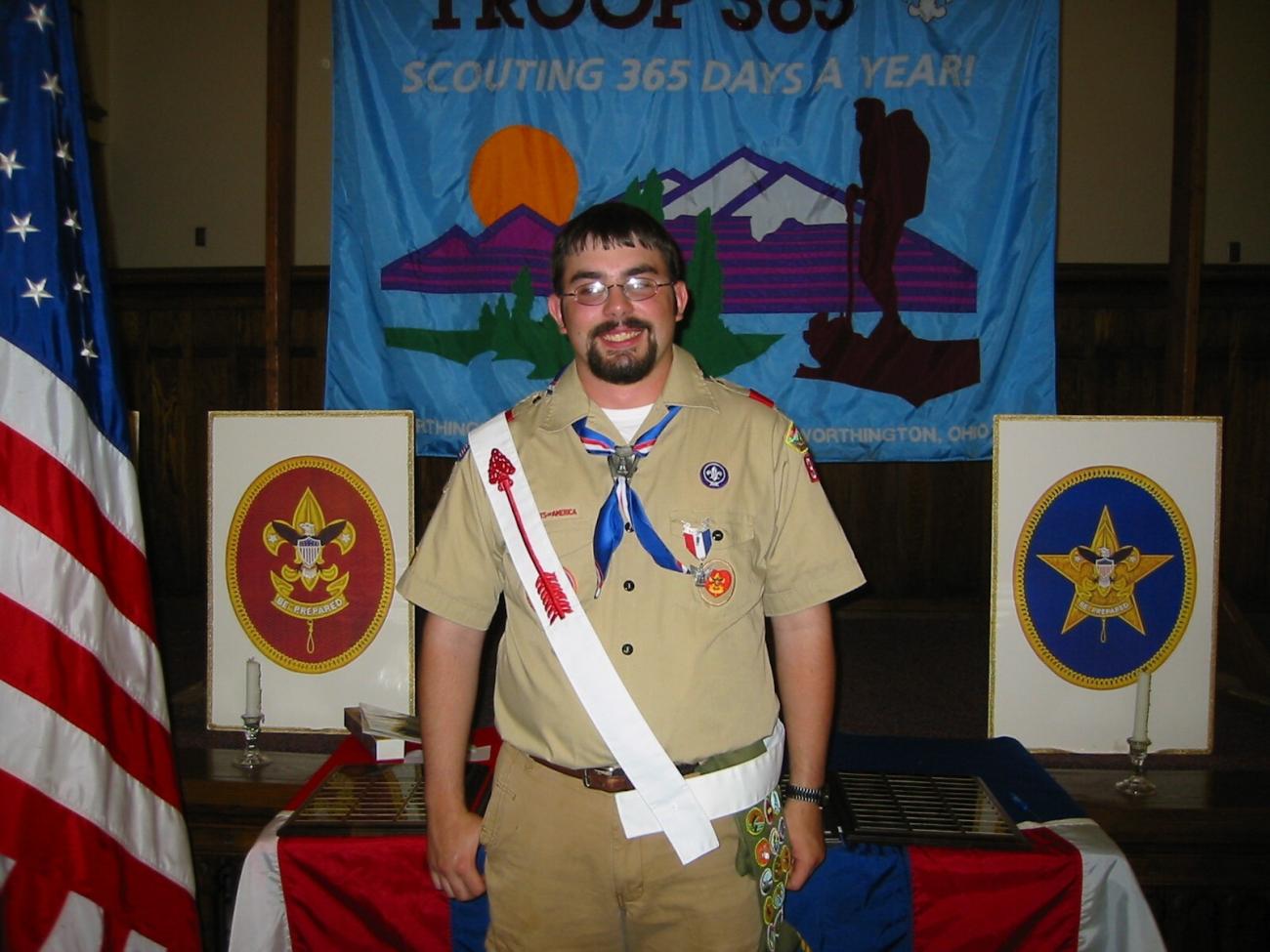 Volunteer Joe Miracle standing in Boy Scout uniform, smiling at camera