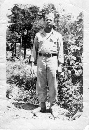 Black and white photo of Herbert McGee Standing in Army uniform in front of vegetation