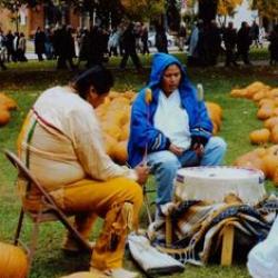 Morning Star Drum Group sits around drum in field of pumpkins