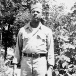 Black and white photo of Herbert McGee Standing in Army uniform in front of vegetation
