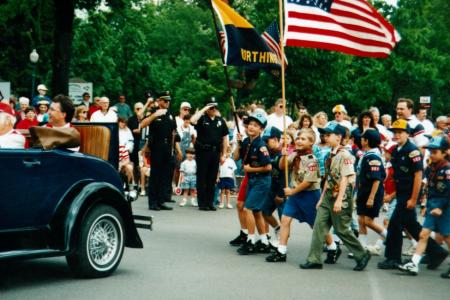 Color photo of a car, Boy Scouts and spectators during a parade