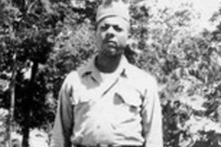 Black and white photo of Herbert McGee Standing in Army uniform in front of vegetation