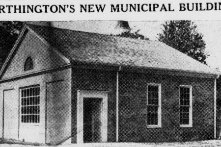 A black-and-white newspaper clipping with a headline above an image of a small brick building over a brief article